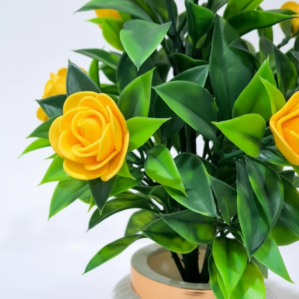 Yellow Camellia-Style Blossoms and lush green foliage in a white, ribbed Plastic Pot