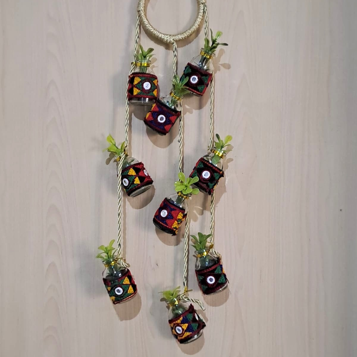 Handmade vertical hanging decoration made of recycled mini glass bottles and golden rope.